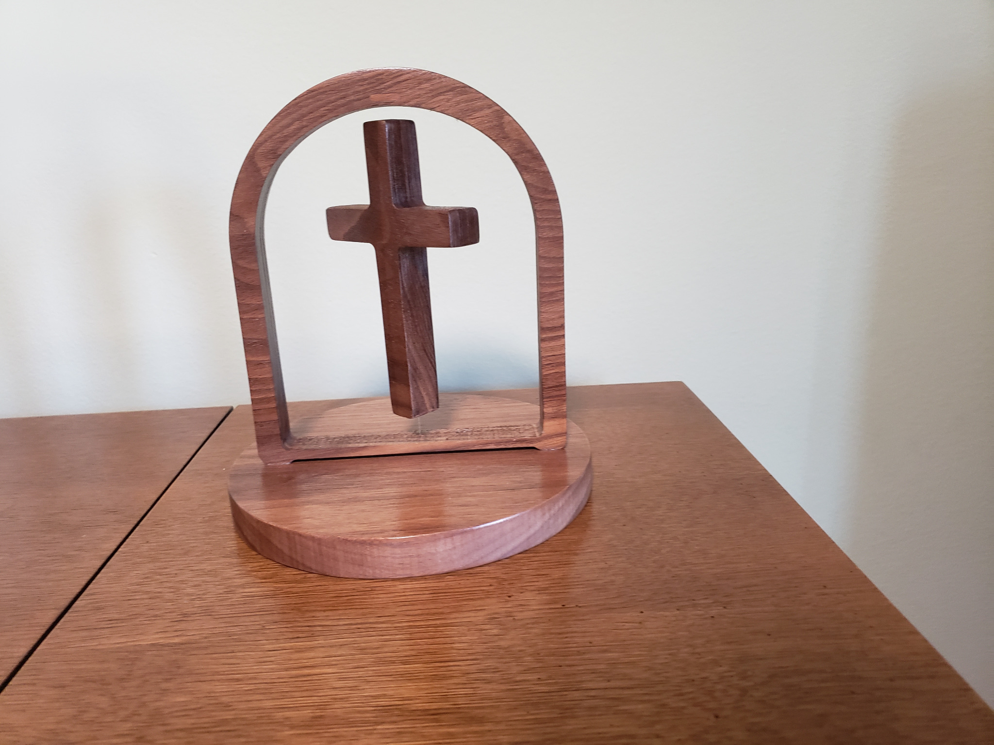 Handcrafted wooden floating cross suspended inside an arch above a round base